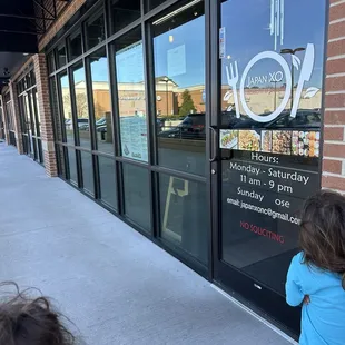 a little girl looking in the window of a restaurant