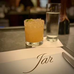a glass of water and a cocktail on a table