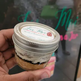 a hand holding a jar of dessert
