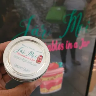 a hand holding a jar of jam