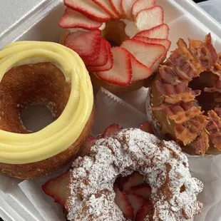 Cronut with custard, glazed donut with strawberries, maple glazed cronut with bacon, and funnel cake donut with Nutella and strawberries