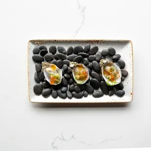 three oysters on a plate with black beans