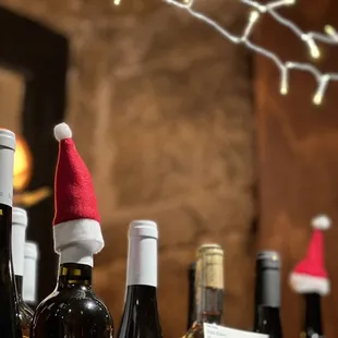 a row of wine bottles with santa hats on them