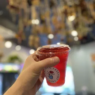 a hand holding a red drink