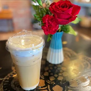 a glass of iced coffee and a vase of flowers