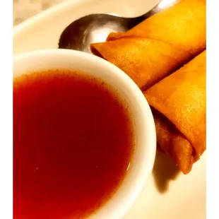 a bowl of soup and two fried spring rolls