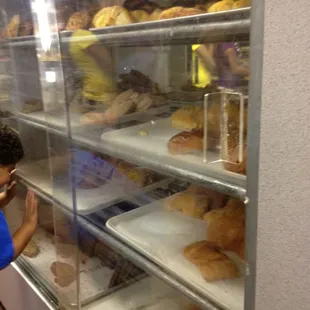 a boy looking at pastries in a display case