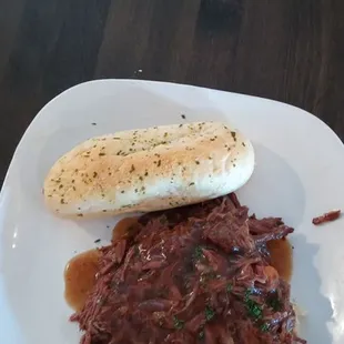 Shredded pot roast on top of mashed potatoes and roll. Lunch special