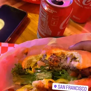 a person holding a sandwich and a can of soda