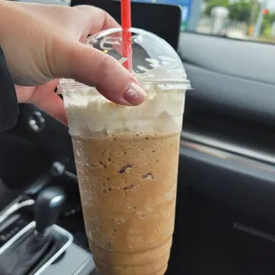 a hand holding a cup of iced coffee