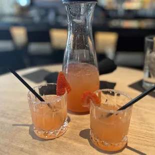 a pitcher of orange juice and two glasses of orange juice