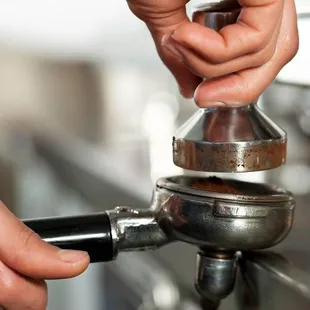 a close up of a person's hand using a coffee grinder