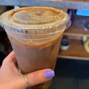 a hand holding a cup of iced coffee