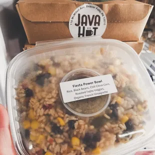 a hand holding a container of rice and beans