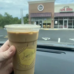 a hand holding a cup of iced coffee