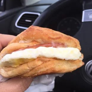 Croissant breakfast sandwich with egg, ham, and Swiss.