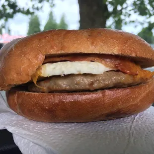 Breakfast sandwich on French toast with egg, cheese, sausage, and bacon.