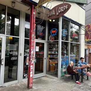 two people sitting on a bench in front of a store