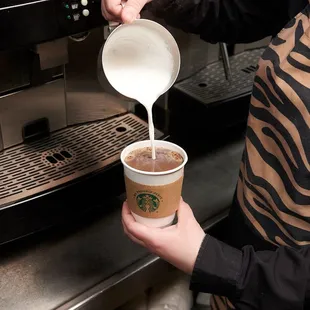 a woman pouring coffee into a cup