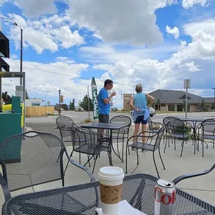 two people sitting at a table outside of a coffee shop