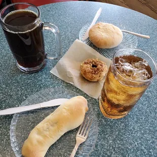 a glass of soda, a hot dog, and a bun on a table