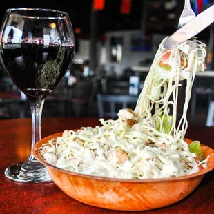 a bowl of noodles and a glass of wine