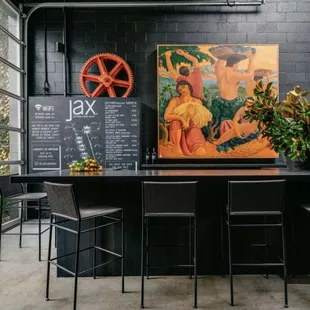 a bar with chairs and a painting