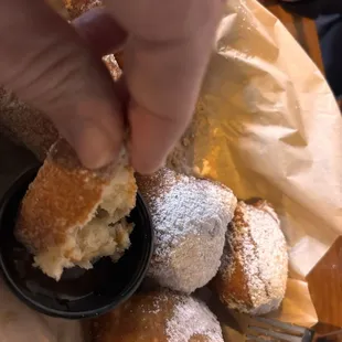 Beignets being dipped in caramel sauce