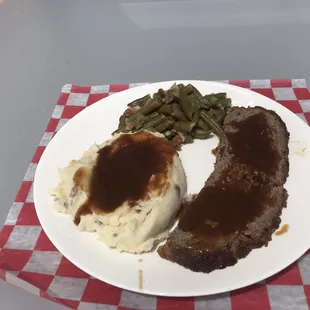 a plate of meat, mashed potatoes and green beans