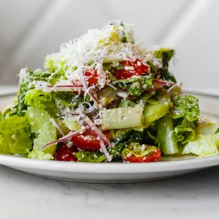 a salad on a plate with parmesan cheese