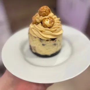 a hand holding a plate with a dessert on it