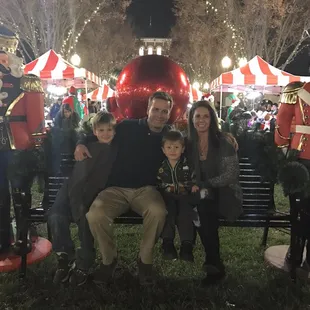 a family sitting on a bench in front of christmas decorations