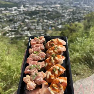 a person holding a tray of sushi