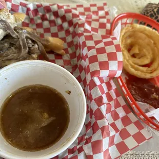 Half eaten French dip , au jus &amp; onion rings delicious