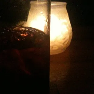 a glass of iced tea with a candle in the background