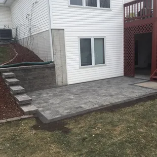 Paver patio with stone retaining wall and mulch beds blocked off by edging in Bennet, NE.
