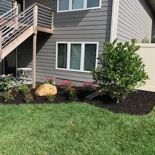 Mulch bed with decorative boulders, shrubs, plants and a PVC fence in Palmyra, NE.