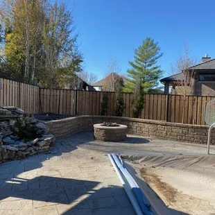 Retaining wall with firepit surrounded by custom wood and ornamental fence in Lincoln, NE.