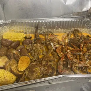 a tray of crab legs, potatoes, corn, and corn on the cob