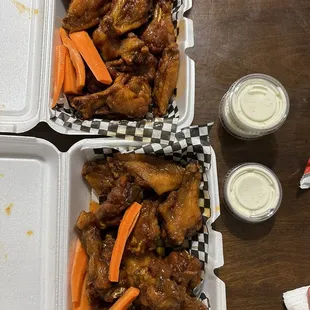 two trays of chicken wings and carrots
