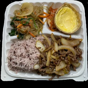 a tray of food with rice, meat, and vegetables