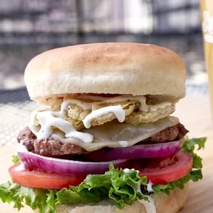 a hamburger with lettuce, onion, tomato, and cheese