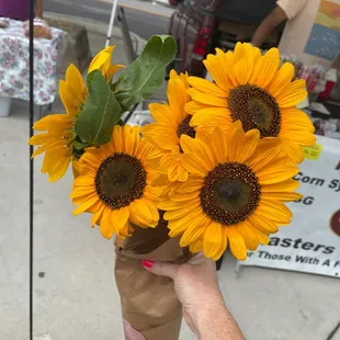 a person holding a bouquet of sunflowers