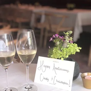 two glasses of wine and a card on a table