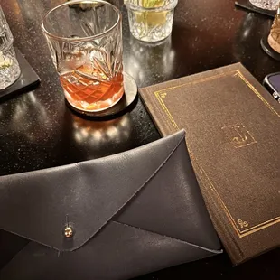 a glass of whiskey and a book on a table