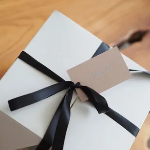 a gift wrapped in white paper with a black ribbon