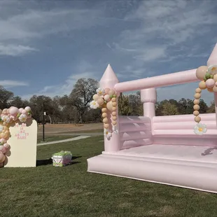 Blossom bounce house with balloon clusters and back drop with balloon garland