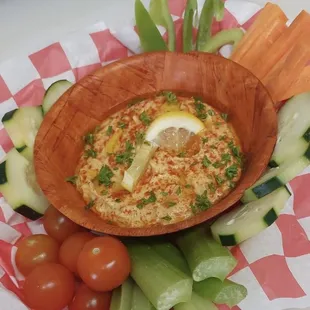 a wooden bowl filled with hummus and vegetables