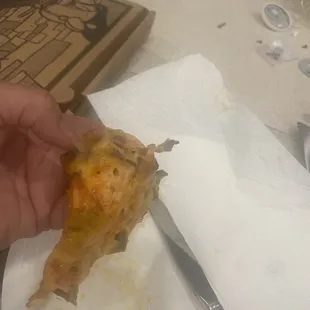 a hand holding a piece of pizza