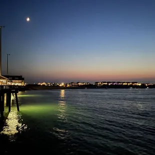 Early evening moon watching over night fishing on the pier.